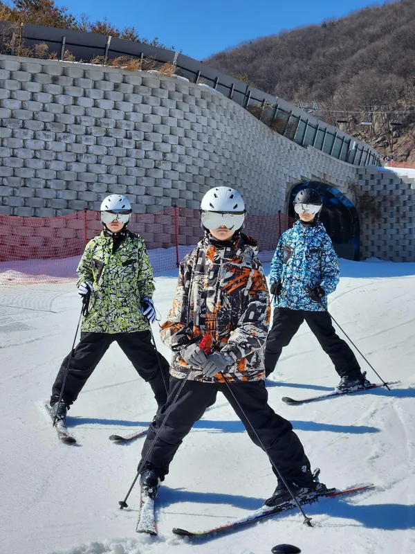 함께 스키를 착용하고 눈 위에 서 있는 라이즌 강습생 세 명